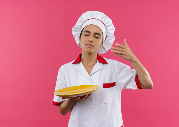 制服闭着眼睛 年轻的女厨师穿着厨师制服 假装拿着盘子上的东西 还有复印空间拿着假装厨师