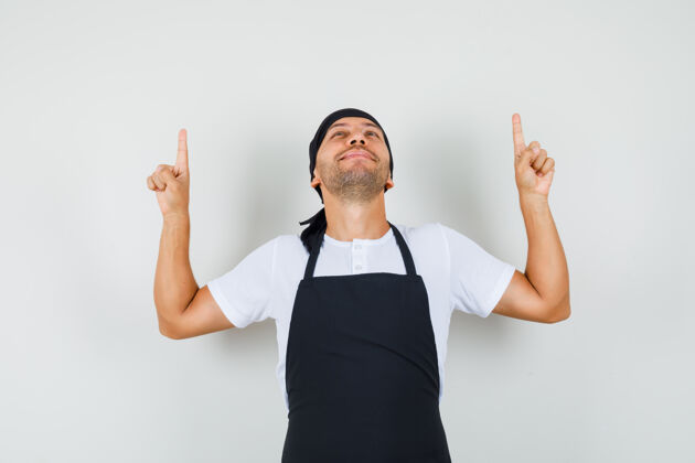 职业面包师穿着t恤 围裙 指着手指 看上去很感激男人工作美食家