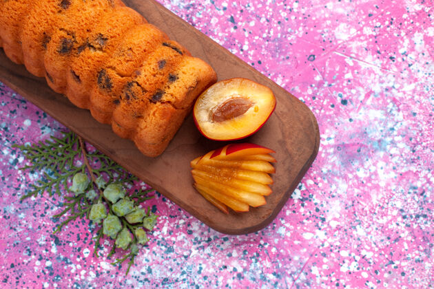 李子顶视图美味的蛋糕甜美可口 粉红色的桌子上有李子粉色烘焙午餐