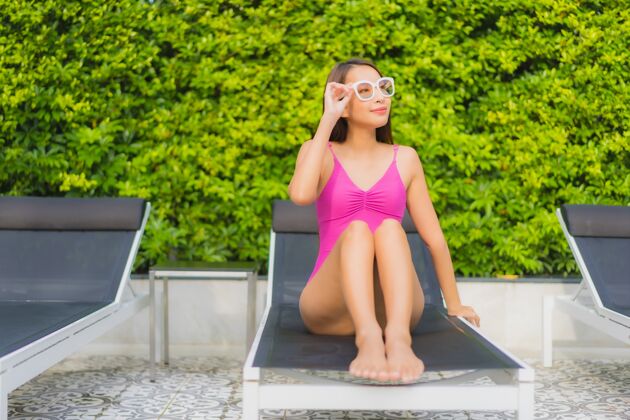 健康肖像美丽的亚洲年轻女子放松微笑周围的室外游泳池在酒店度假村海滩亚洲游泳