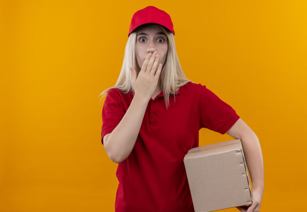 手一个穿着红色t恤和帽子盒的年轻女孩把她的手放在孤立的橙色背景上的嘴上嘴盒子T恤