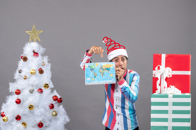 指向正面图是一个戴着螺旋弹簧圣诞帽的男人用手指着地图印刷帽子圣诞节