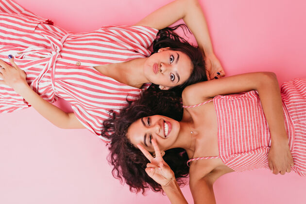 休闲模特模样的女孩们 穿着粉色带白色条纹的衣服 仰面躺着扭动着可爱娱乐欢快
