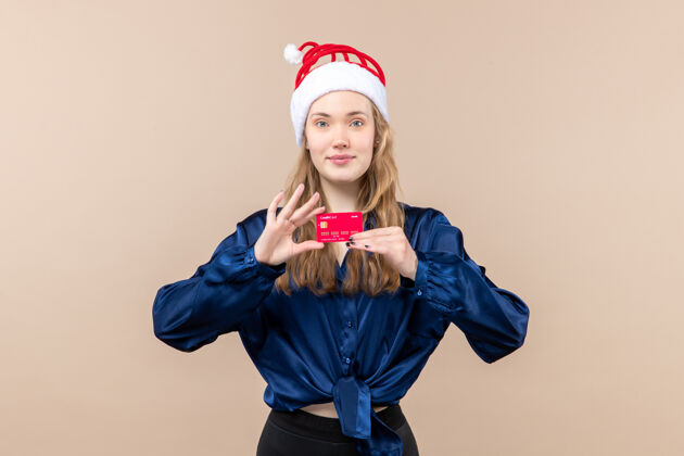 年轻女性正面图年轻女性手持粉色背景的红色银行卡过节照片新年感慨圣诞钱肖像圣诞节年轻