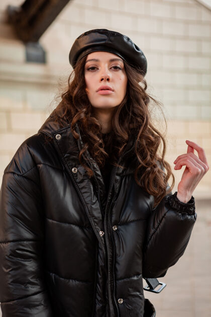 优雅时尚女人摆出冬秋时尚潮流黑色羽绒服和皮帽贝雷帽在古老美丽的街道穿着高跟鞋街头服装服装