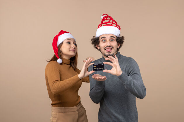 圣诞老人圣诞心情激动满意酷酷情侣戴红色圣诞老人帽出示银行卡兴奋酷男