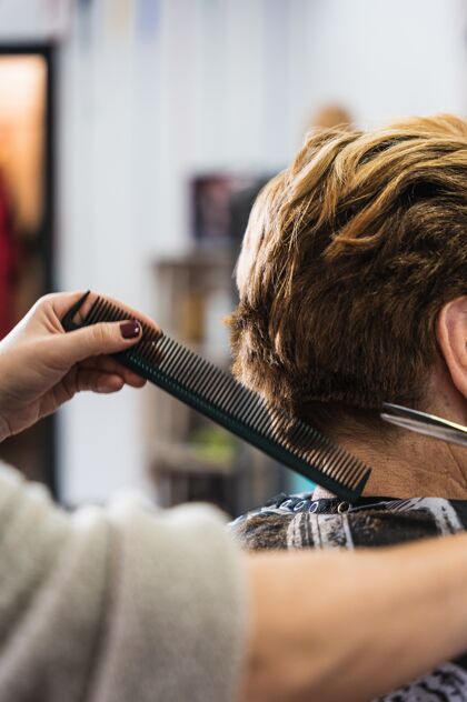 明亮在美容院理发师剪女人短发的垂直特写风格头发着色
