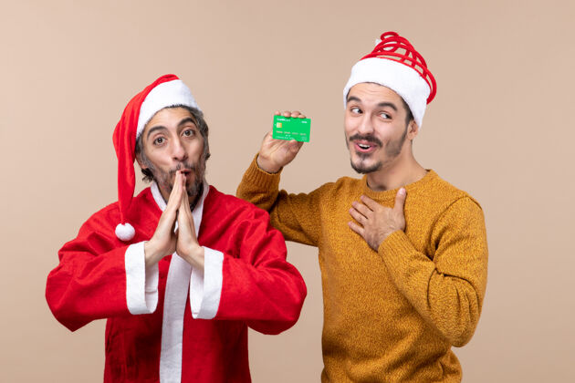 圣诞老人正面图两个快乐的家伙 一个穿着圣诞外套 另一个手放在胸部 背景是米色的米色两个前面
