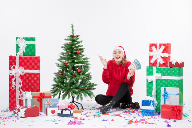 圣诞树前视图年轻女子围坐在白墙上拿着飞机票的礼物抱着人情感