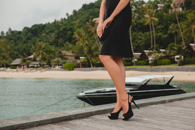 鞋类双腿穿着黑色高跟鞋的奢华性感迷人的女人穿着黑色礼服摆在码头上的豪华度假酒店 暑假 热带海滩年轻船女人