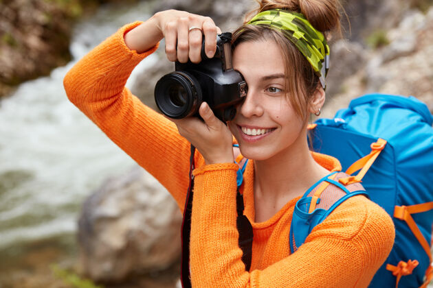 爱好穿着亮橙色套头衫的年轻高加索女游客的特写镜头放松举行刷新