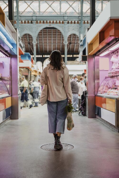 杂货店市场上拿着购物袋的女人的后视图流行病爆发垂直