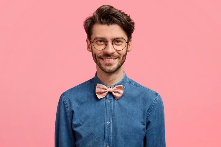 衬衫照片中的帅哥笑容可掬 发型新潮 神采奕奕 身着时尚喜庆的服装 站在粉色的墙上酷胡须胡茬