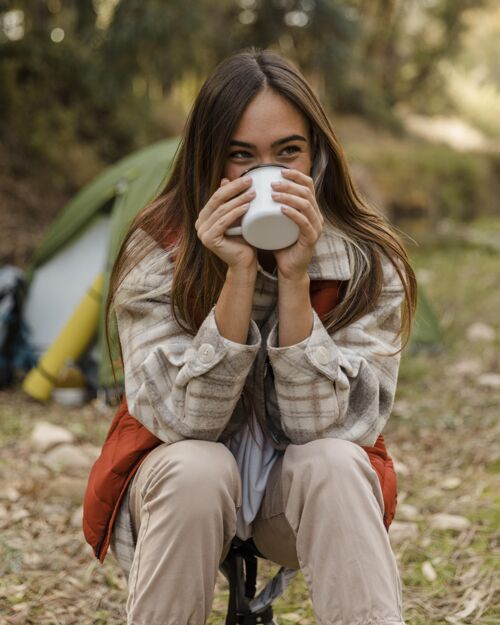 树木快乐的野营女孩在森林里用杯子喝酒旅行旅行者木材