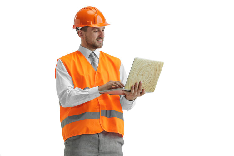 男性一个穿着建筑背心 戴着橙色头盔 带着笔记本电脑的建筑工人建设者建筑师专业