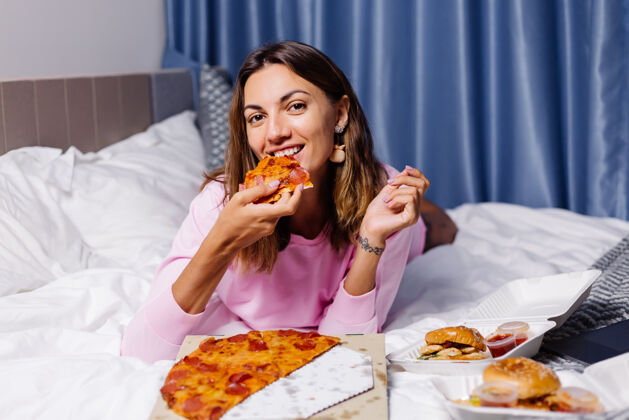 快乐女人在家吃披萨盒子卧室晚餐