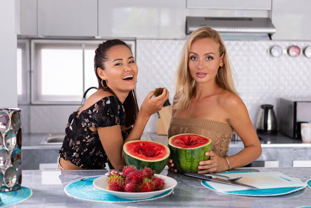 夏天两个女朋友在厨房吃西瓜和红毛丹热带水果吃烹饪一餐
