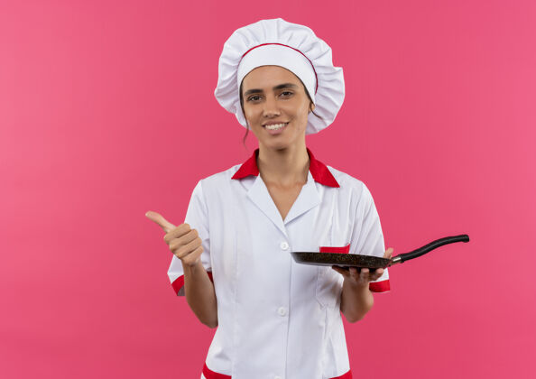 厨师面带微笑的年轻女厨师身穿厨师制服 手拿煎锅 拇指朝上 留着复印空间拇指平底锅拿