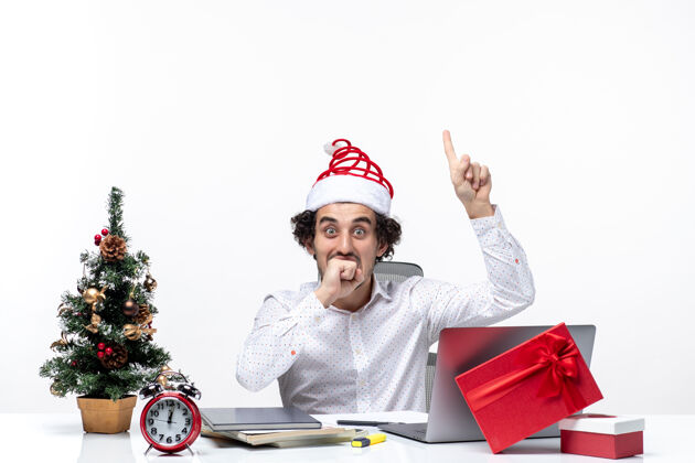 微笑在白色背景的办公室里 快乐积极的年轻商人戴着滑稽的圣诞老人帽子 脸上露出惊讶的表情惊讶帽子电脑