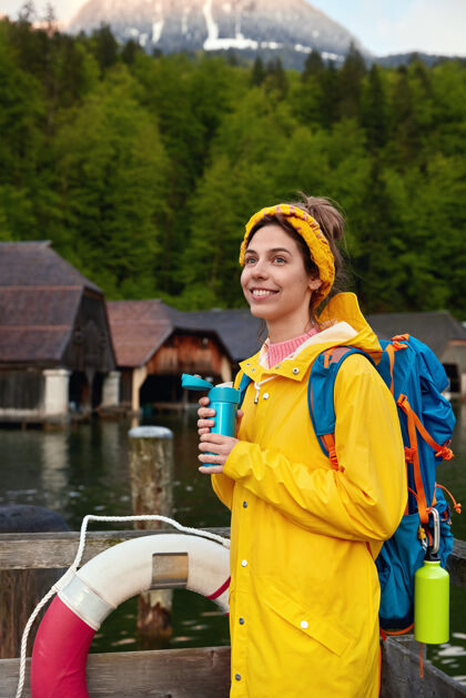 背包穿着黄色雨衣的微笑女性的垂直镜头Anorak树山