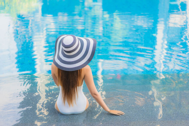 太阳镜肖像美丽的亚洲年轻女子放松微笑周围的室外游泳池在酒店度假村豪华棕褐色游泳