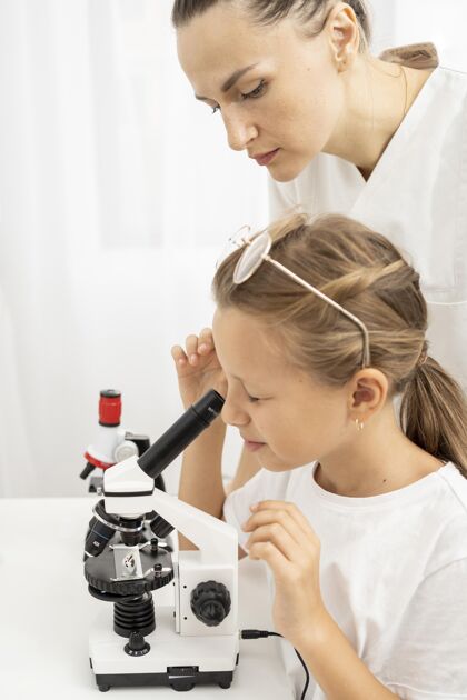 女孩和女老师一起学看显微镜的女孩孩子科学知识