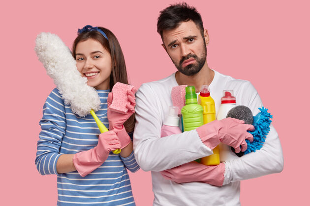 高兴一家人一起分担家务快乐的女士拿着擦灰尘的海绵 白色的刷子 有着愉快的表情家庭消极化学