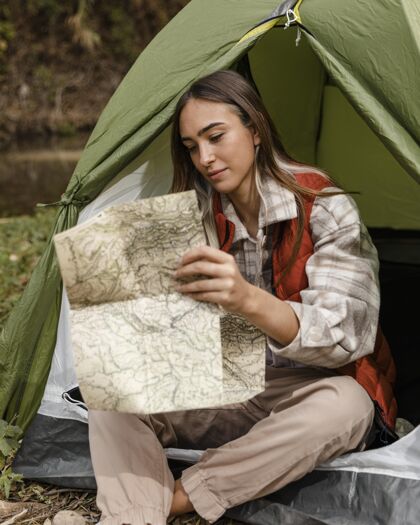 木材快乐的野营女孩在森林里查看地图自然旅行冒险