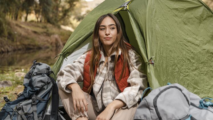 旅行快乐的野营女孩在森林里坐在帐篷前看旅行探险户外