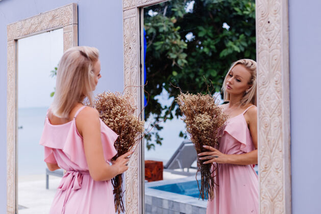 肖像浪漫写真的粉红色晚装可爱的女人手持野花在豪华热带别墅外美丽的女性与花束健康户外黑发