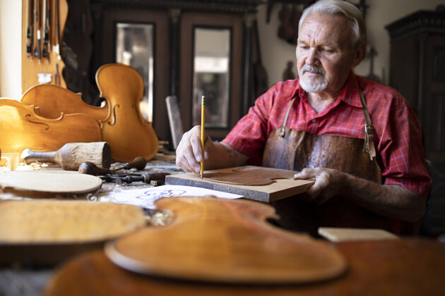 木匠资深木匠在他的老式木匠作坊里制作小提琴乐器木工小提琴工匠