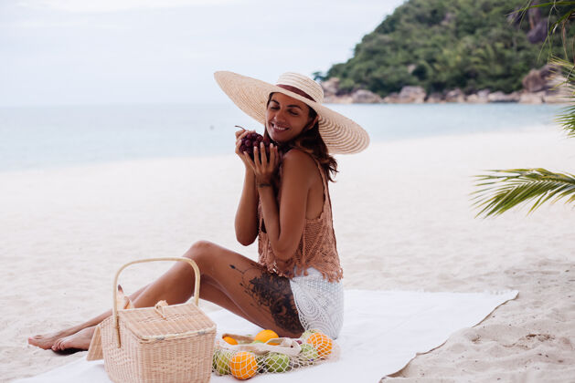 米色年轻漂亮的白种人 皮肤黝黑 穿着针织衣服 戴着帽子在沙滩上健康款式成人