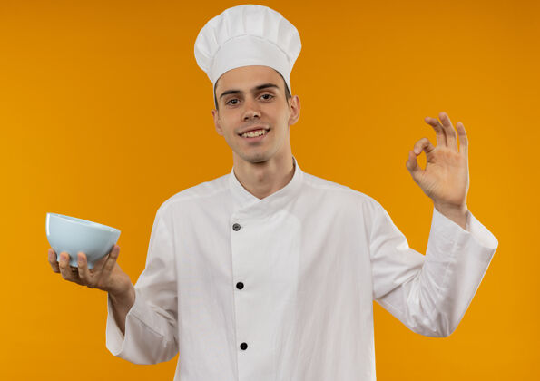 厨师笑容可掬的男青年酷酷地穿着厨师制服拿着碗 摆出很好的姿势手势男穿着