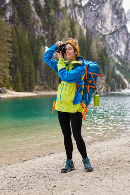 自然快乐女人的垂直镜头拍自然景观的专业照片 穿夹克独自山积极