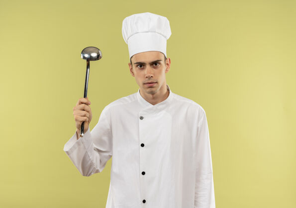 厨师年轻的男厨师穿着厨师制服 手里拿着勺子 站在隔离的绿墙上 留着临摹的空间厨师穿勺
