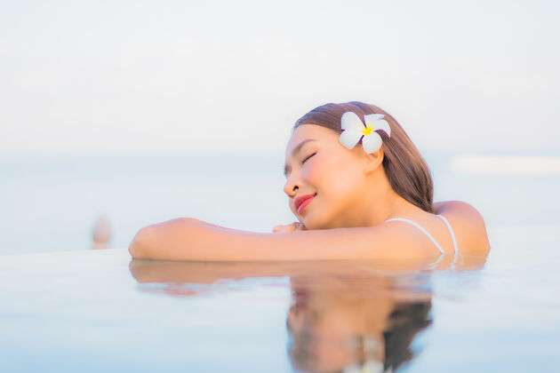 海洋肖像美丽的亚洲年轻女子放松微笑周围的室外游泳池在酒店度假村放松泳装酒店