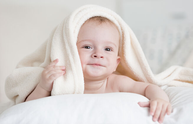 裸体可爱的男婴躺在床上的白色毯子下的画像毯子谎言毛巾